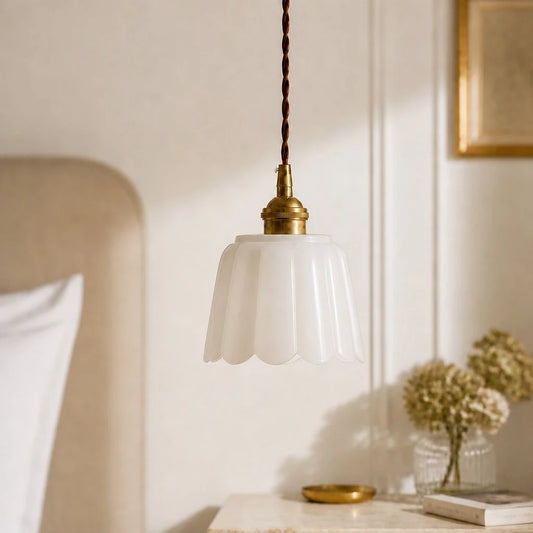 Pendant light with white glass shade and brass fixture on a neutral background
