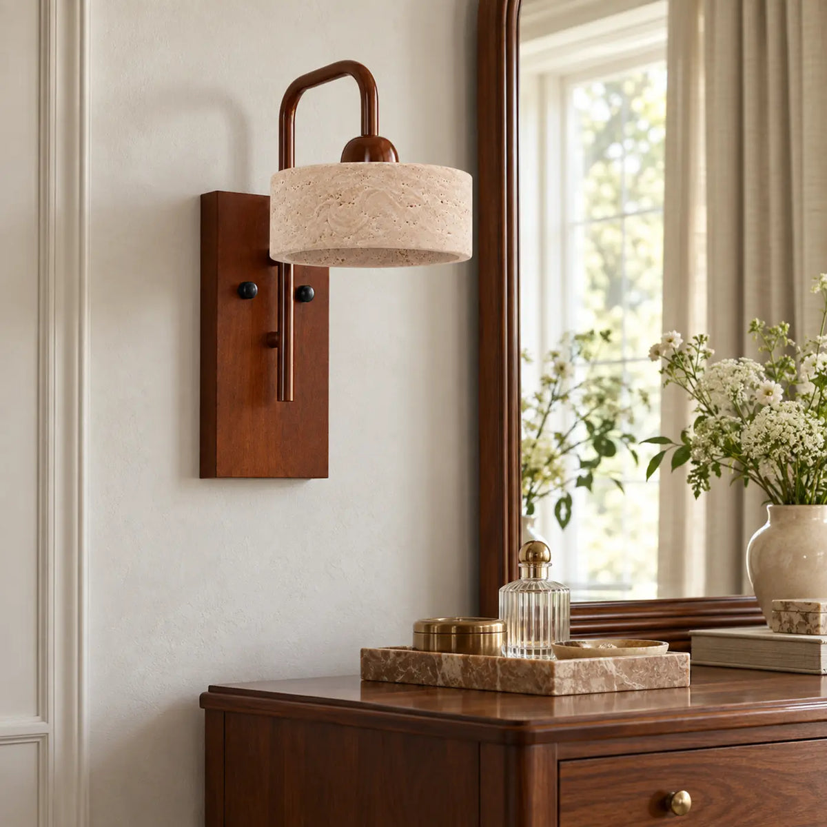 Straight travertine cylinder wall light with walnut base beside a dresser