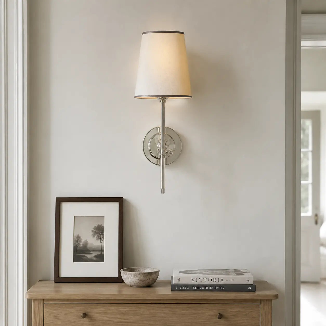 Chrome linen shade wall light above a hallway console
