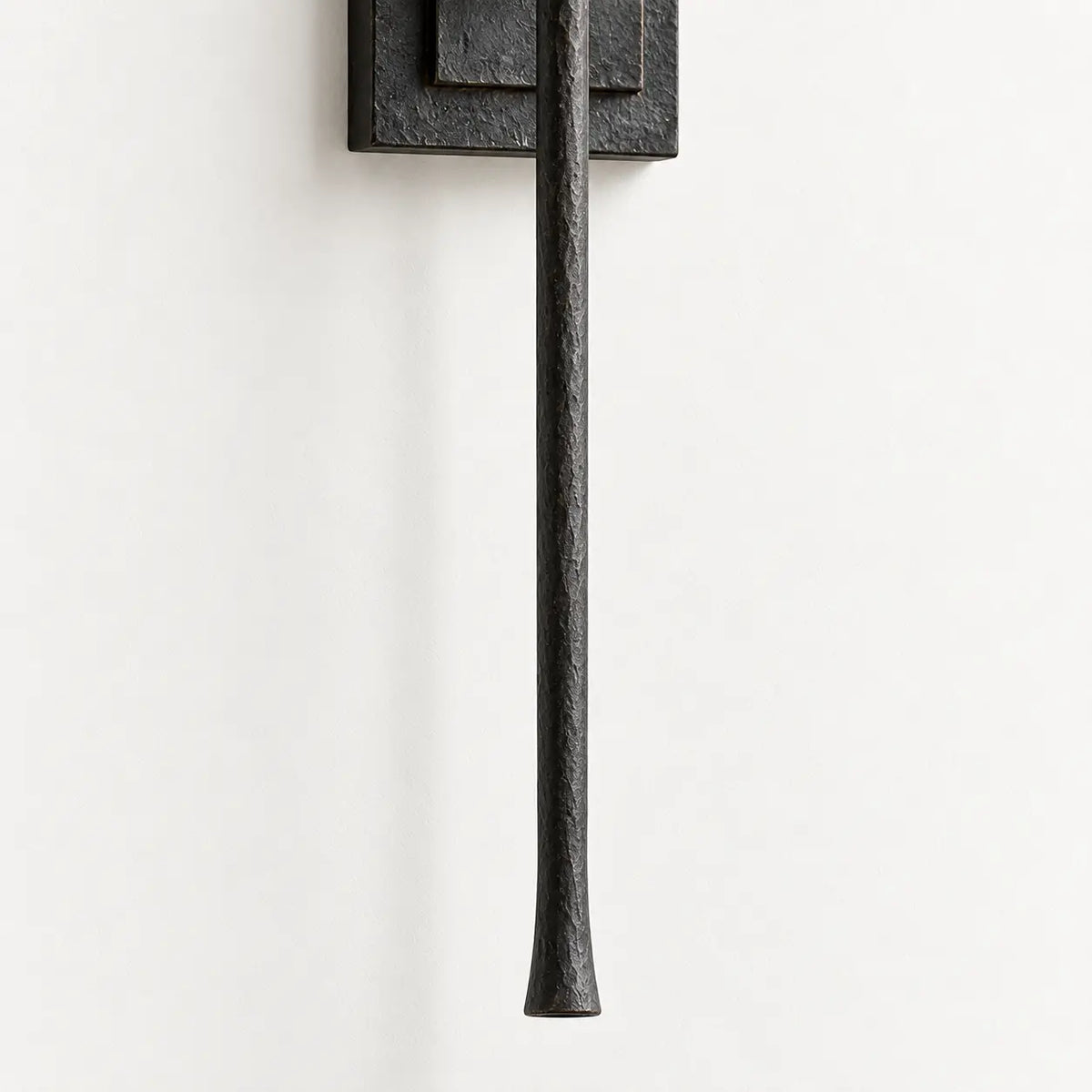 Tapered end of long black vertical wall light rod