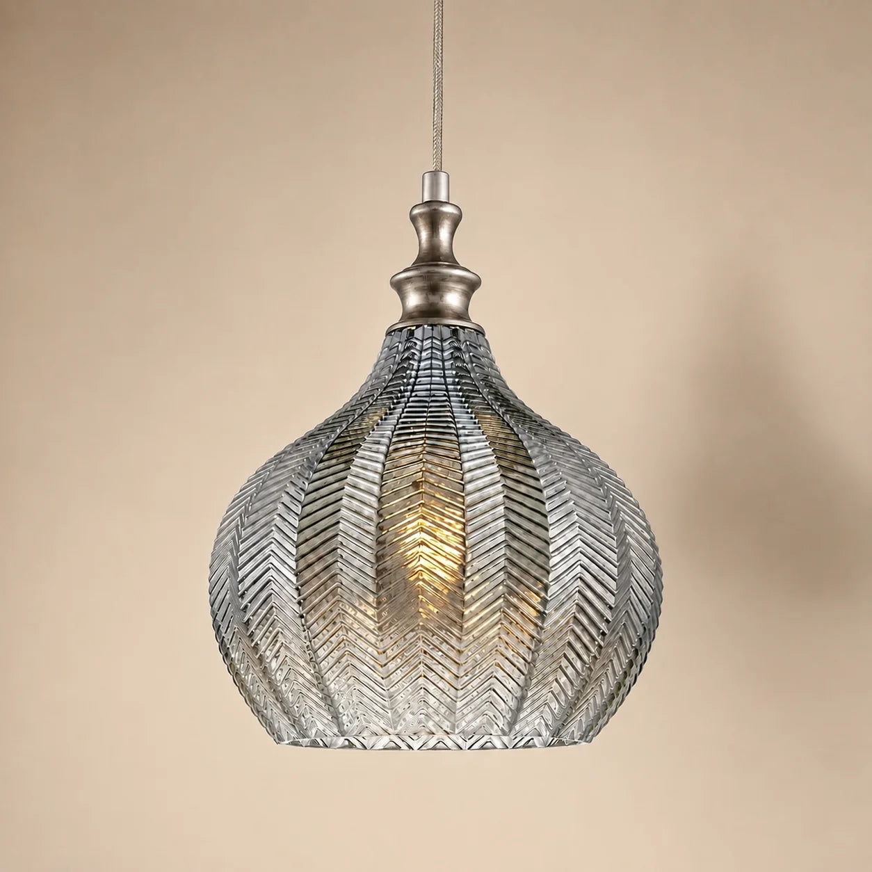 Round smoke grey Solenne pendant light on a warm beige studio background