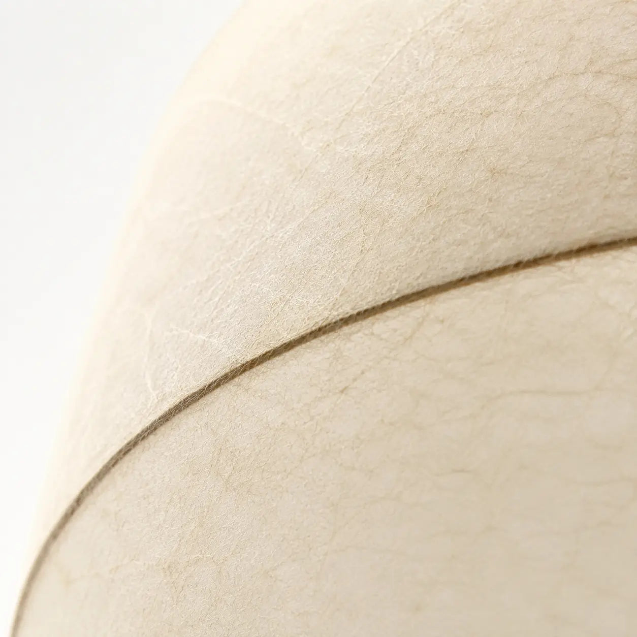 Close detail of the ivory cocoon fibre texture and dark seam edge