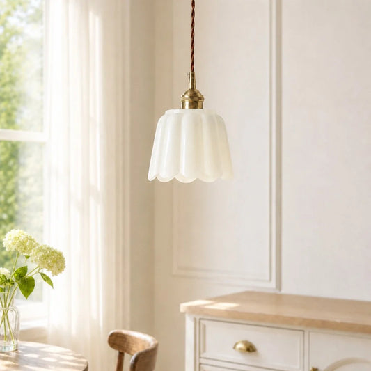 Pendant light fixture hanging in a room with a window and wooden furniture.