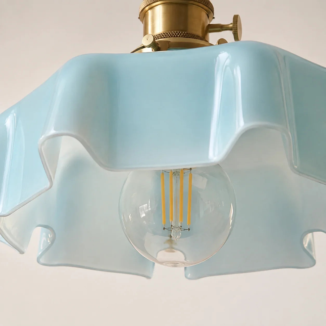 Sharp close-up of the Elowen soft blue scalloped glass edge and clear bulb