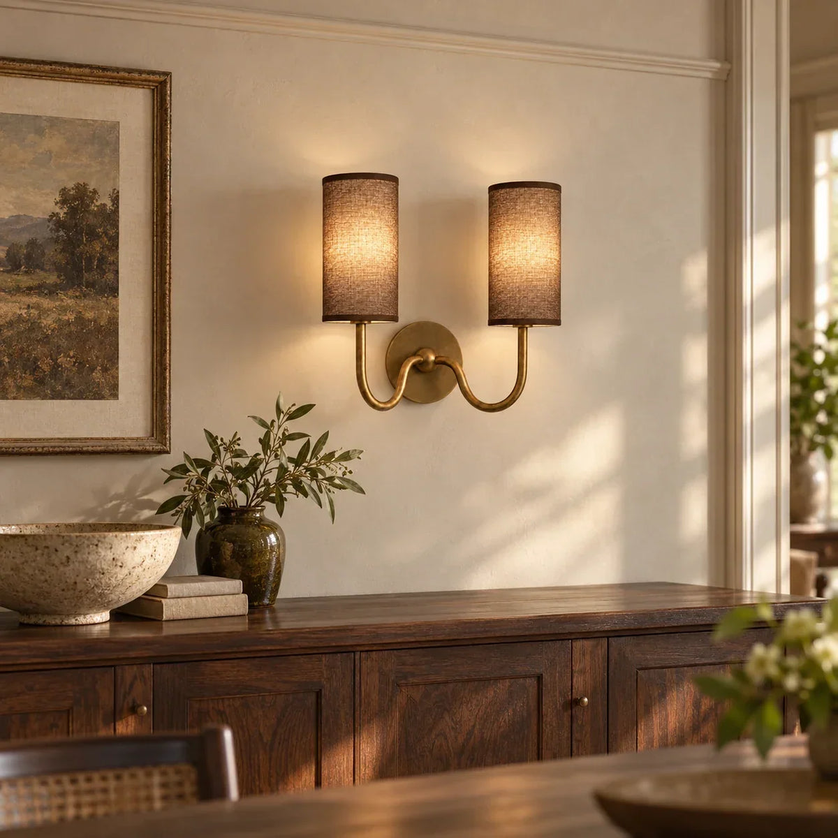 Tumbled brass double wall light with coffee linen shades above an oak sideboard