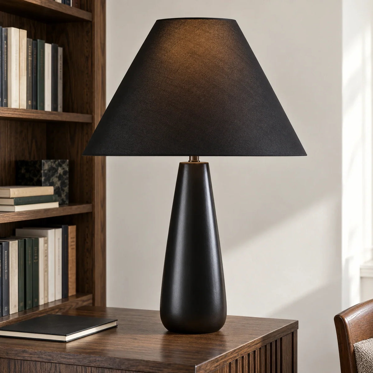 Ceramic black tapered table lamp on a library console