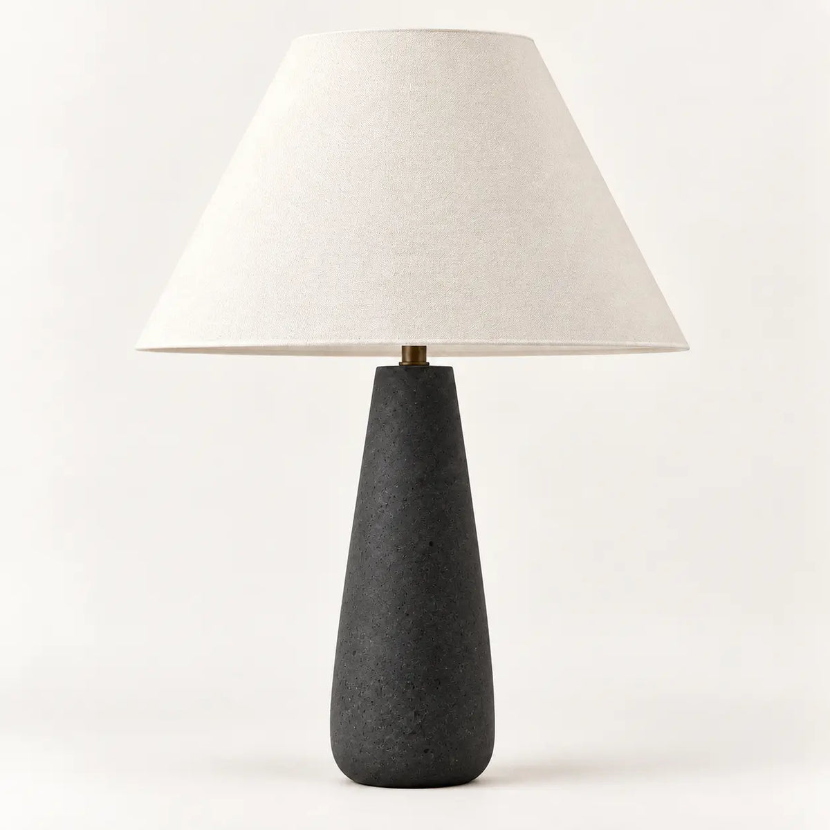 Concrete black tapered table lamp with cream textile lampshade, studio view