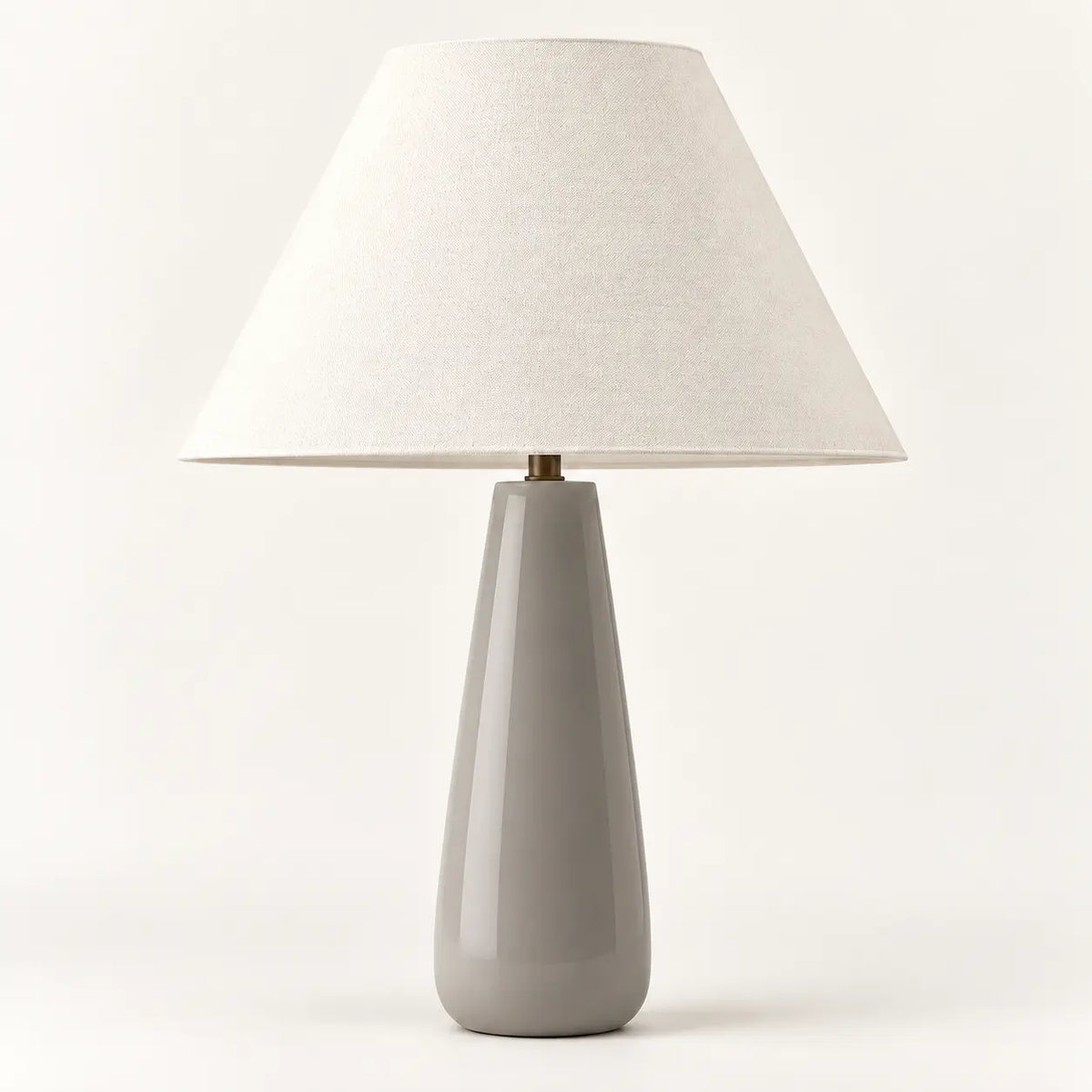 Ceramic grey tapered table lamp with cream textile lampshade, studio view